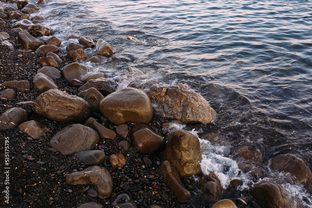  Seashore with pebbles and stones in the evening at sunset