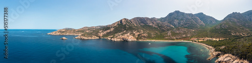 Panoramic view of a lone catamaran moored in a large rocky cove on the west coast of Corsica on the turquoise Mediterranean sea