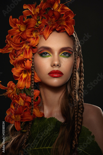Portrait of a beautiful girl with bright makeup decorated with fresh flowers lilies