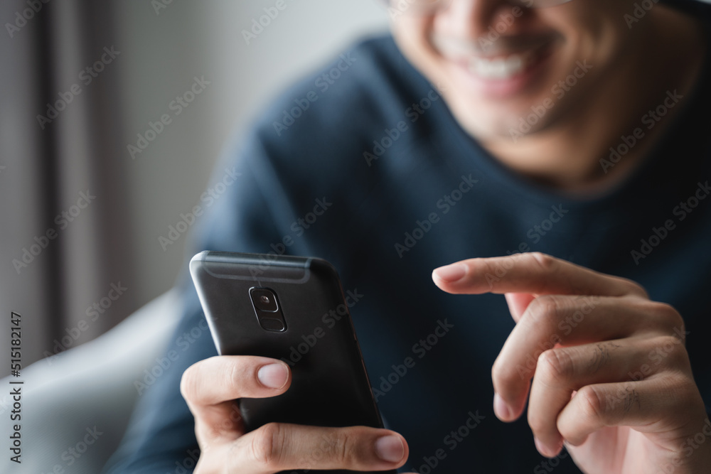 Happy Asian man using smartphone on sofa in living room at home, searching data and social media on internet. Happy Asian man using smartphone on sofa in living room at home, searching data and social media on internet.