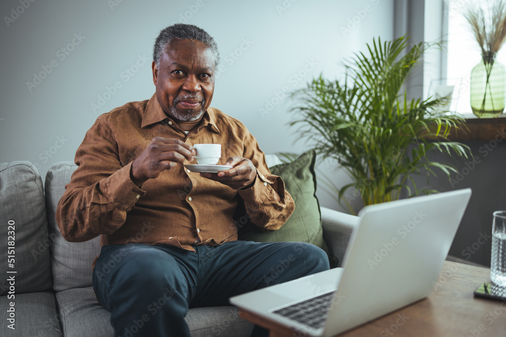 Mature handsome man sitting on the sofa drinking coffee. A senior black man enjoys a cup of coffee at home. Elderly man at home drinking coffee