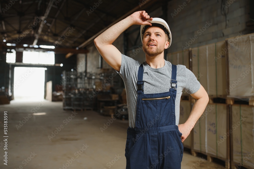 Portrait of happy male worker in warehouse standing between shelves.
