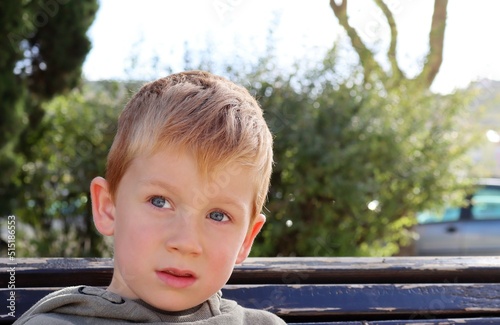 The blond boy looks dreamily into the distance. A thoughtful five-year-old boy.