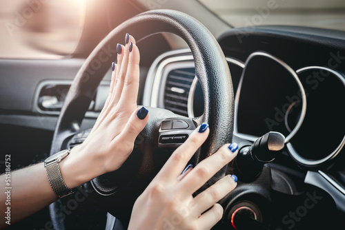 Woman pressing honk button on steering wheel. Female hand honking while driving a car. © Evgenia