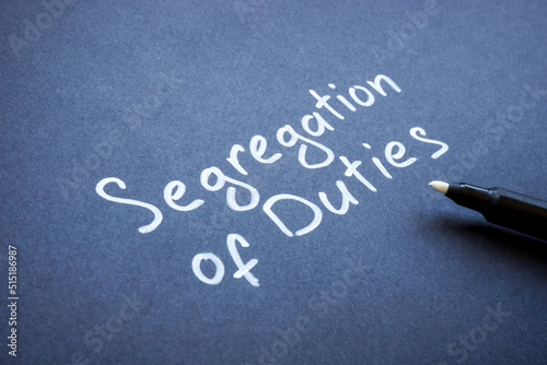 Handwritten words Segregation of duties on the dark paper. photo