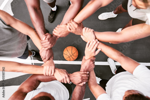 Athletes showing trust and standing united. Men expressing team spirit with their hands joined huddling at a basketball game. Sportsmen holding wrists in huddle for support and unity at sports match. photo