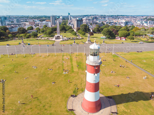 Aerial drone shot of a red and white striped lighthouse on the coast in Plymouth, UK photo