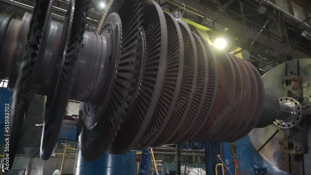 Manufacturing of Heavy Duty Gas Turbines. Rotating Compressor Component Fixed on a Big Testing Machine. Machining Process. Operator supervising the Work. Inside a Production Facility. Heavy industry.