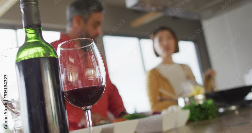 Happy diverse couple cooking together, mixing ingredients in pan in kitchen Happy diverse couple cooking together, mixing ingredients in pan in kitchen