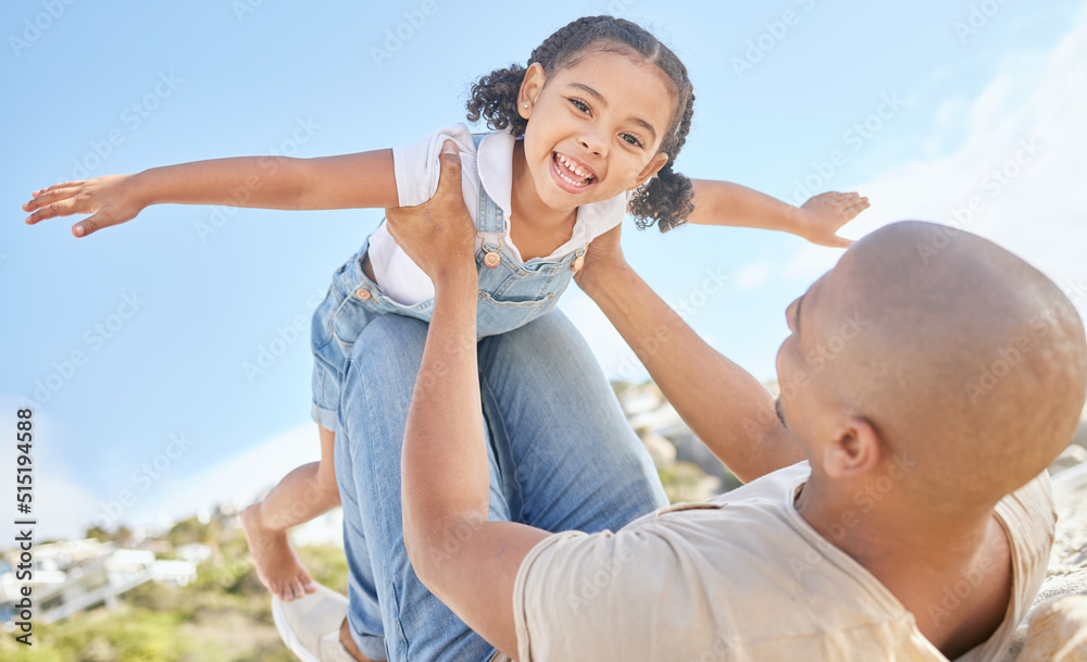 Father and daughter bonding together outdoors. Portrait of adorable little girl from below having fun pretending to fly like a superhero with arms outstretched while being held by her loving dad. Father and daughter bonding together outdoors. Portrait of adorable little girl from below having fun pretending to fly like a superhero with arms outstretched while being held by her loving dad.