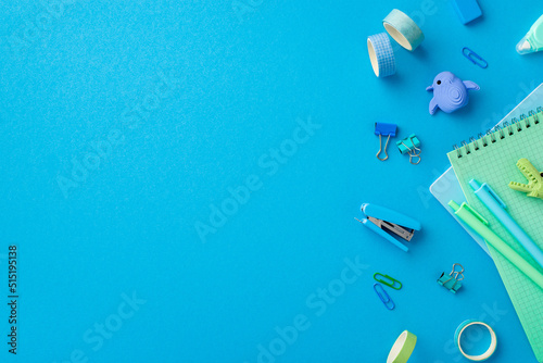 School accessories concept. Top view photo of stationery animal shaped erasers adhesive tape mini stapler binder clips pens and copybooks on isolated blue background with empty space