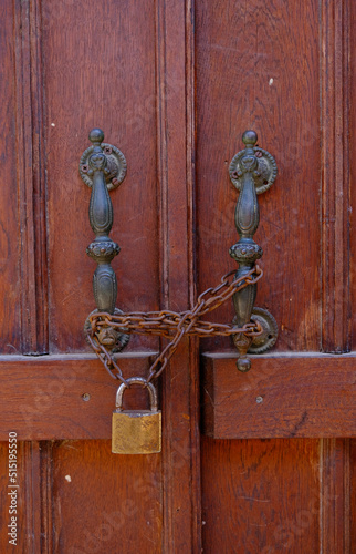 Old wooden door locked with chain from door handles. No entrance, chained door.