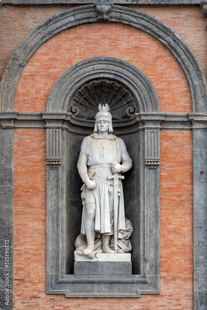 Marble statue of medieval king decorating a niche in the exterior facade of a building in Napoli