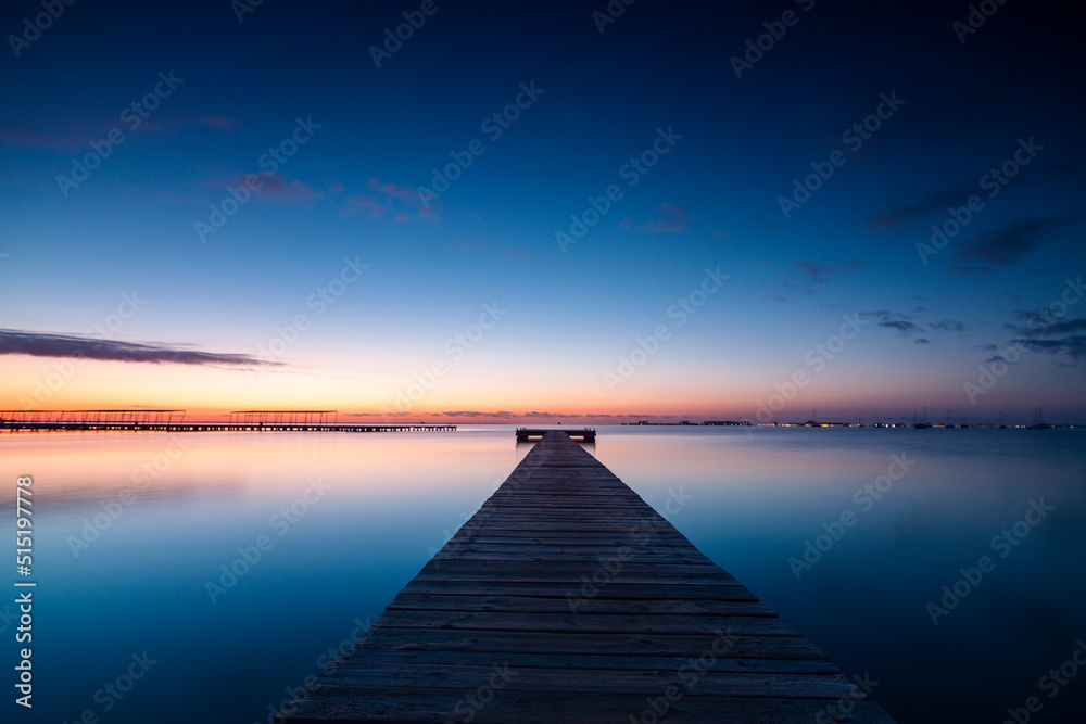 Horizontal photo of the sunrise and the calm waters of the Mar Menor, Region of Murcia, Spain, from a wooden jetty in San Javier