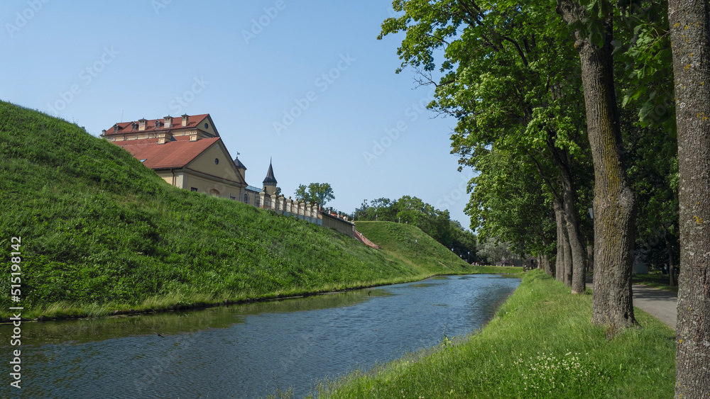 Naklejka premium Fortress moat with water reflecting trees and castle walls. Bridge over the moat.
