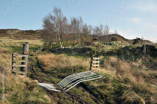 high pennine farmland with a broken gate across a pathway leading to midgley moor in calderdale west yorkshire photo