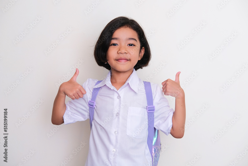 Asian kid wearing school uniform and backpack smiling and give two thumb up Asian kid wearing school uniform and backpack smiling and give two thumb up