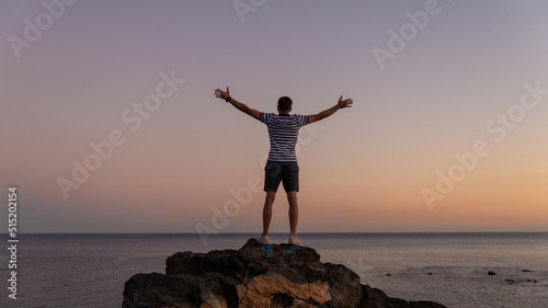 Carriages man standing on rock in win pose in sunset.