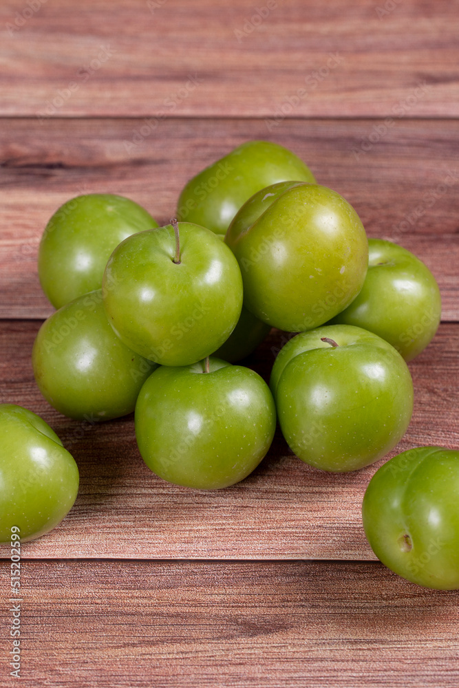 Green plum on wood background. Pile of green plums. close up Green plum on wood background. Pile of green plums. close up