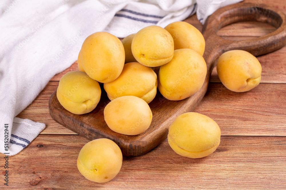 Apricots on wood background. Stack of fresh apricots in a wooden serving plate. close up