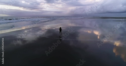 Dream concept. A girl running on an empty beach at sunset silhouette. Drone shot
