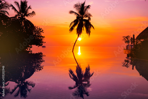 Fototapeta Naklejka Na Ścianę i Meble -  Sunset on Maldives island, luxury water villas resort and wooden pier. Beautiful sky and clouds and beach with palms background for summer vacation holiday and travel concept.