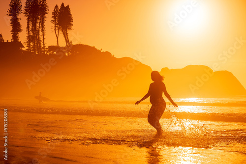 Happy pregnant woman on coastline at tropical beach with sunrise or sunset tones © artifirsov