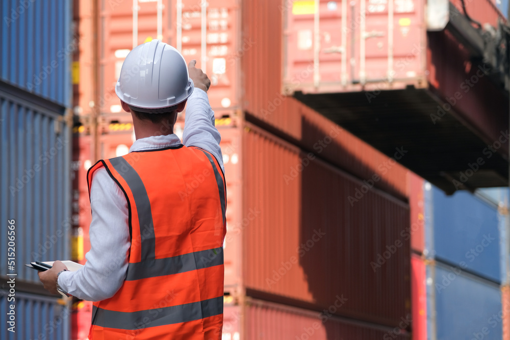 Fototapeta premium Caucasian foreman holding tablet and points his finger to control the loading position of containers.