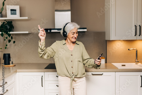 Smiling elderly woman dancing to her favourite music at home photo