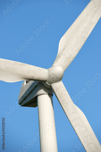 A wind turbine and rotor blades isolated against a blue sky on a sustainable, eco friendly farm. Low angle view of harvesting a biodegradable energy source to generate electricity from windy climates