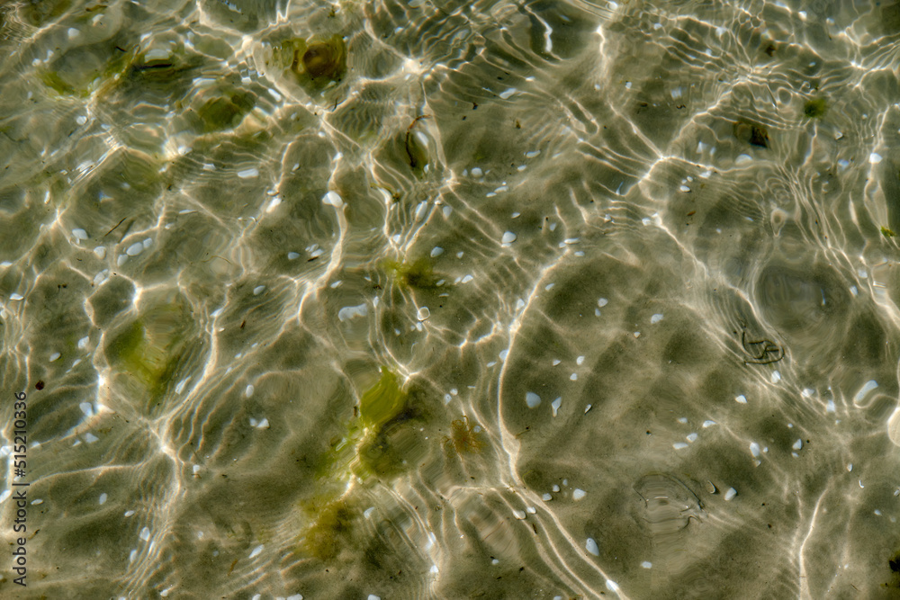 Clear beach water on a summer day with copy space. Top view of calm low tide sea ripples during spring. Closeup of the bright sun reflection shining off the shallow ocean useful as a background Clear beach water on a summer day with copy space. Top view of calm low tide sea ripples during spring. Closeup of the bright sun reflection shining off the shallow ocean useful as a background