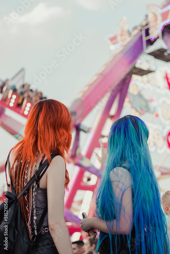 Two friends with their backs to each other looking at the amusement park