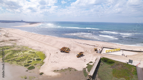 Esposende, Portugal, April 10, 2022: Aerial view of the two sides of Restinga de Ofir. Esposende fishing harbor maintenance dredging. Dumper vehicles and rotating excavator parked on the sand. photo