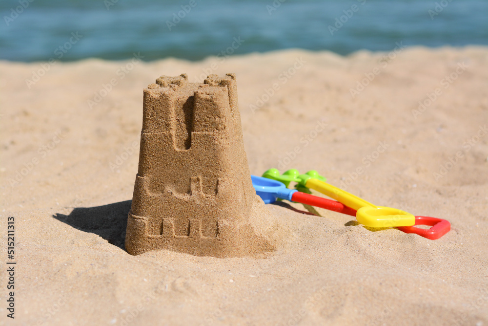 Sand castle and child plastic toys on beach near sea. Space for text Sand castle and child plastic toys on beach near sea. Space for text
