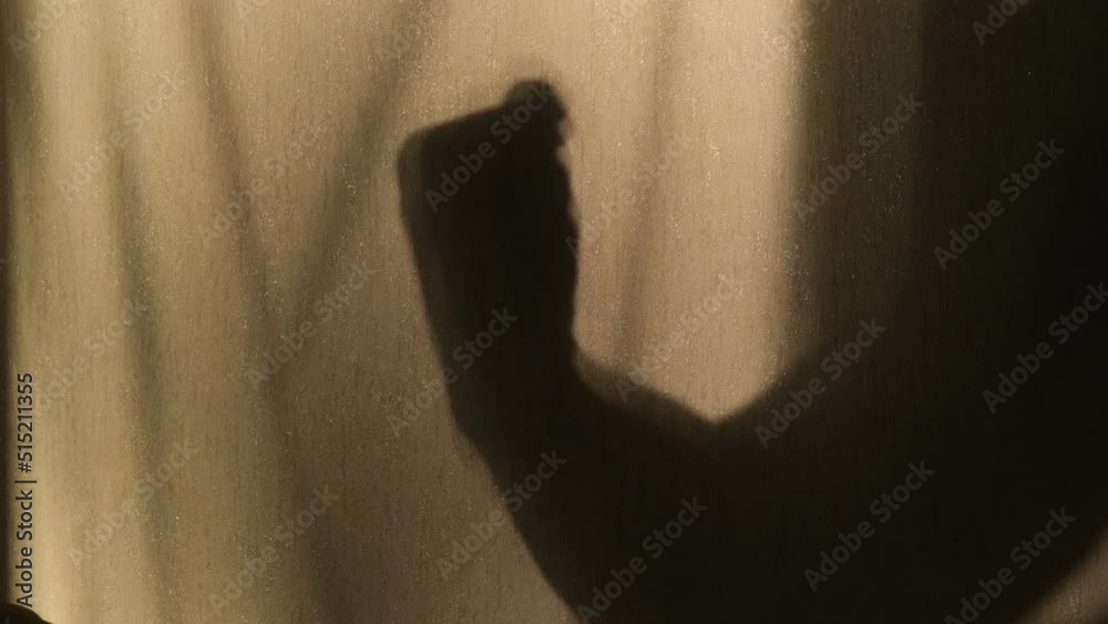 Shadow of a hand threatening someone with a fist, close-up Shadow of a hand threatening someone with a fist, close-up
