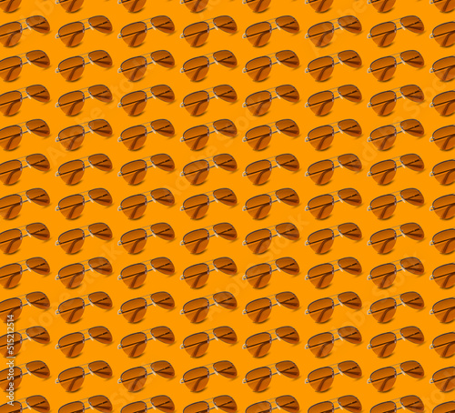 Many stylish sunglasses on orange background. Seamless pattern design