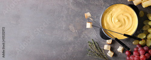 Flat lay composition with pot of delicious cheese fondue on grey table, space for text. Banner design