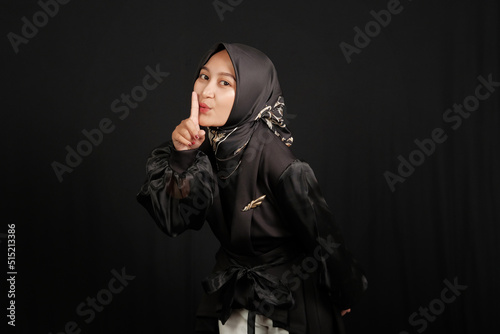 Happy and excited Asian Muslim girl in a black shirt on black background