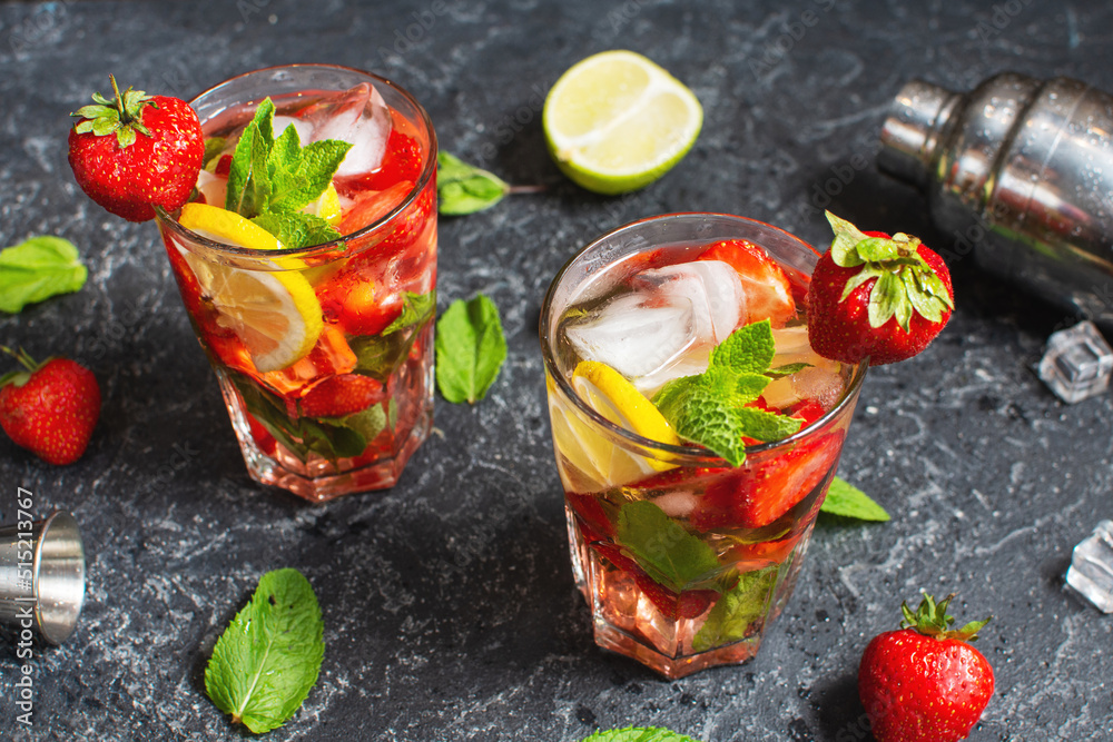 Summer refreshing mojito cocktail with strawberry, mint and lime with shaker for whipping drinks on a dark stone table Summer refreshing mojito cocktail with strawberry, mint and lime with shaker for whipping drinks on a dark stone table