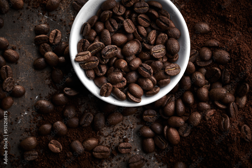 Fototapeta premium Roasted coffee beans in bowl isolated close up on brown grunge background