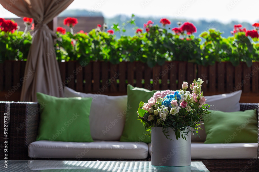 Obraz premium A rose bouquet in a box on a summer terrace. A bouquet of pink and white roses decorated in a hat box created by a florist.