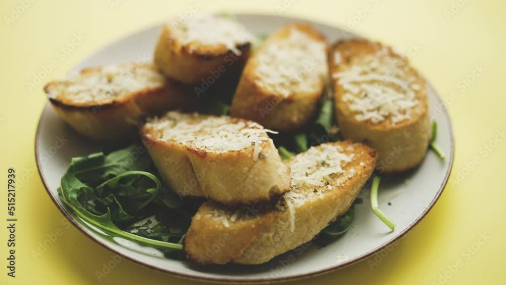 Slices of garlic cheese bread served on a plate arugula leaves Slices of garlic cheese bread served on a plate arugula leaves