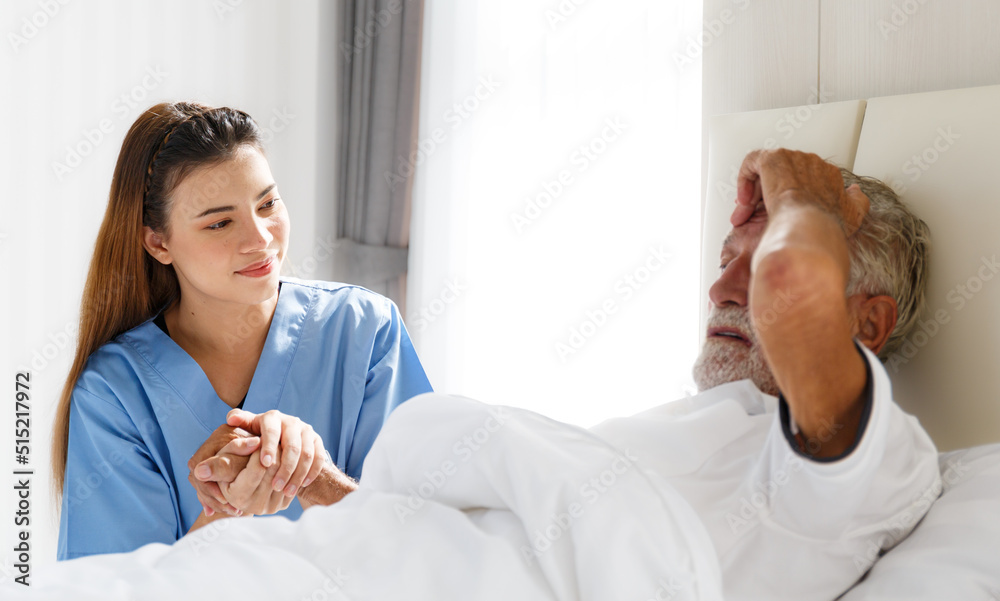 Obraz premium The young doctor held the hand of an old Caucasian man to take care of him. Talk to him from his illness lying in bed in his bedroom