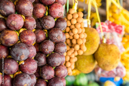 Mangosteen, Lanzones and Marang Fruits hanging in a fruit stall at a public market. Exotic tropical fruits for sale. photo