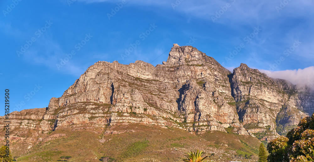 Low angle view of Table Mountain against a bright blue sky. Rocky mountain peak in South Africa. Scenic landscape of a remote hiking location on a sunny day. Travel and explore nature on adventure