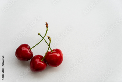 Cherries with stalks on the table. Three cherries isolated on white background with copy space for text. Selective focus.