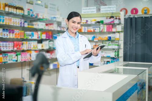 Portrait of female pharmacist using tablet in a modern pharmacy drugstore.