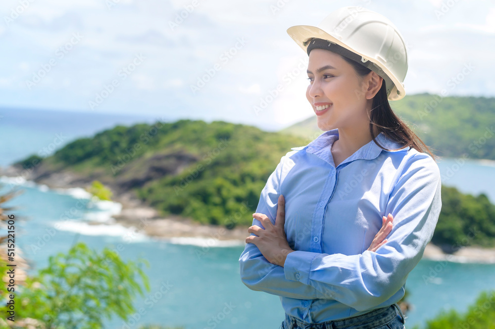 Female engineer working on the seaside wearing a protective helmet . Female engineer working on the seaside wearing a protective helmet .