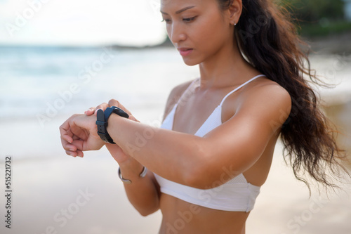 Young Beautiful woman in Bikini relaxing and using smartwatch on the beach, Summer, vacation, holidays, and health concept.