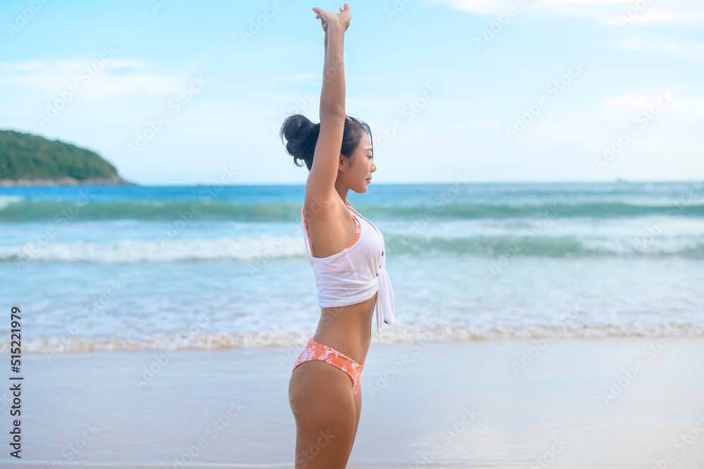 Young asian woman in bikini doing yoga on the beach, health and meditation concept Young asian woman in bikini doing yoga on the beach, health and meditation concept